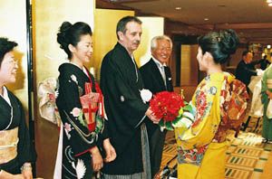 신혼 부부 양옆에 서 있는 중매인. 여성 중매인은 기혼 여성의 정장 기모노(5개 문장이 있는 검은색 기모노), 남성은 양복을 입은 예