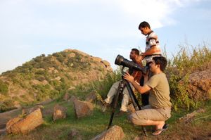 무거운 망원 렌즈 부착물을 장착한 사진작가들이 삼각대를 사용하여 카메라를 안정시켜 선명한 이미지를 얻는다