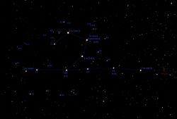 옷걸이 성단 (Cr 399). 주요 10개 별 중 8개의 겉보기 등급이 표시되어 있다. 동쪽 6개 별이 만드는 직선과 비슷한 각도 간격을 가진 산개 성단도 함께 표시되어 있다. 가장 서쪽 별은 다른 별들보다 간격이 좁다.